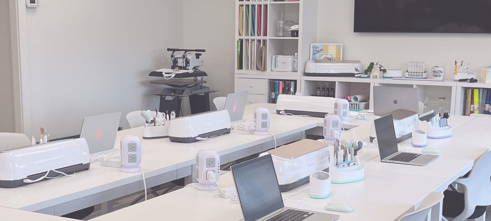 Modern crafting space with desks, laptops, Cricut machines and tools.