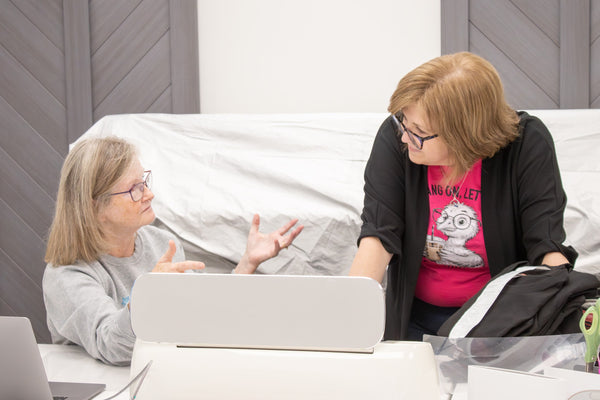 Two makers chatting at a Cricut station during a workshop